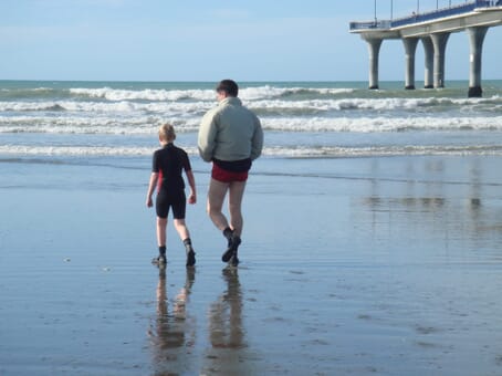 Grant and Mark walk on beach to open water surf in New Brighton, NZ
